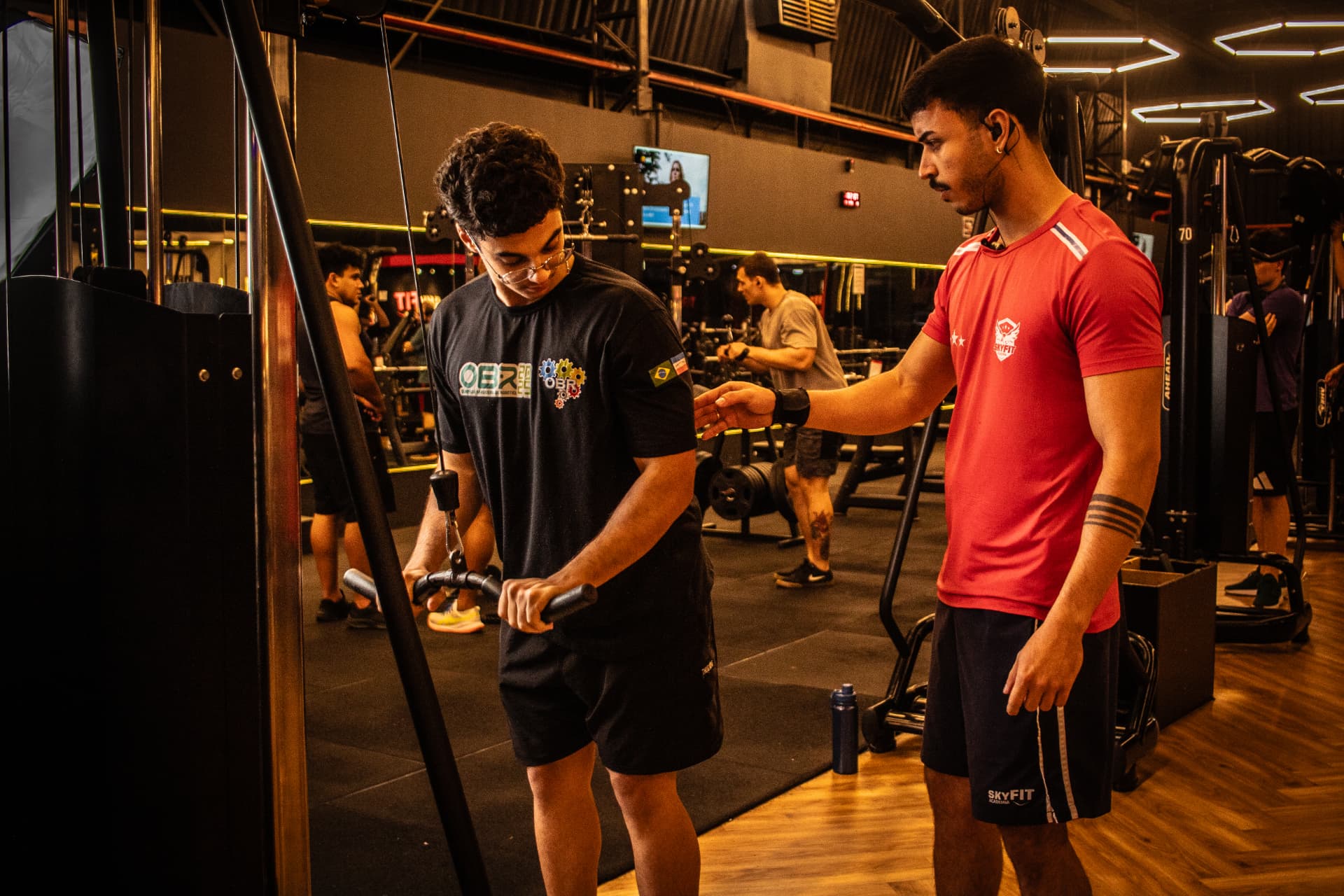 Aluno treinando no cross-over com orientação do professor na SkyFit Egas